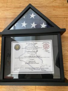A framed document and flag on top of a table.