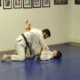 Two people are practicing judo on a blue floor.