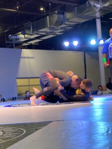 Two men wrestling on a mat in an indoor arena.