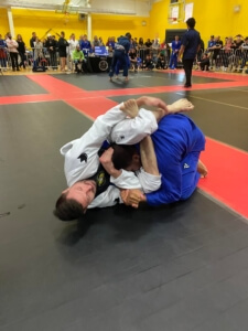 A man in blue and white uniform wrestling on the ground.