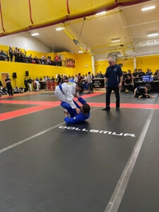 A man in blue and white wrestling on a court.