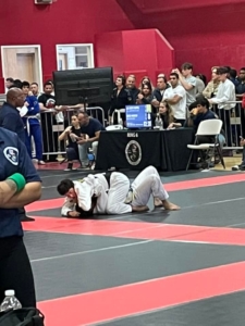 A man is wrestling on the ground in front of an audience.