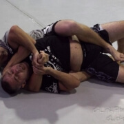 Two men wrestling on a white floor.