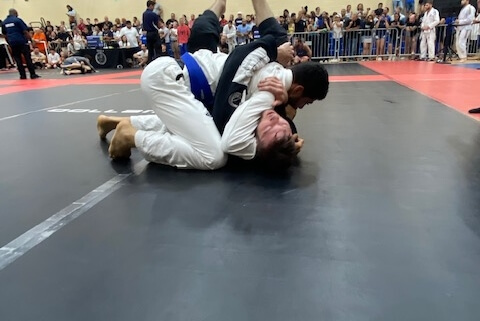 A man is wrestling on the ground in a gym.