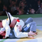 A man in white shirt and black pants wrestling on ground.