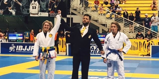 Three people in suits and white belts on a court.