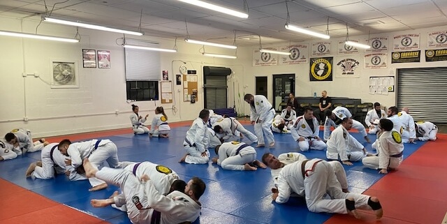 A group of people in a room with some on mats
