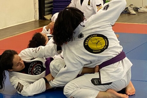 A woman is doing a judo move on another girl.