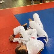 A person in white and blue uniform on red mat.