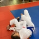 A person in white and blue uniform on red mat.