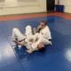 Two men are practicing judo on a blue mat.