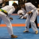 Two people in white uniforms are practicing judo.
