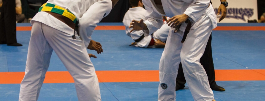 Two people in white uniforms are practicing judo.