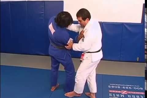 A man in white and blue uniform practicing judo.