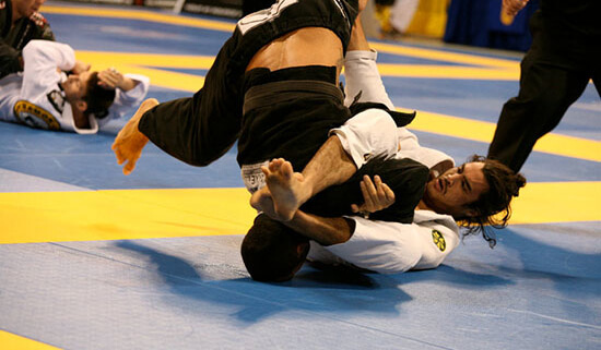 Two people are wrestling on a blue and yellow mat.