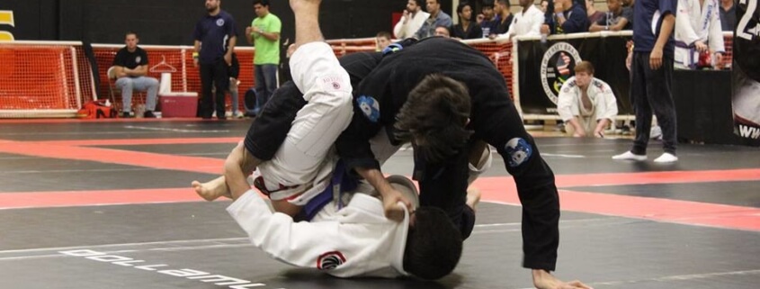Two people in a judo match on the ground.