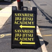 A sign on the side of the road that says savarse jiu jitsu academy.