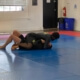 Two people are practicing jiu jitsu on a blue mat.