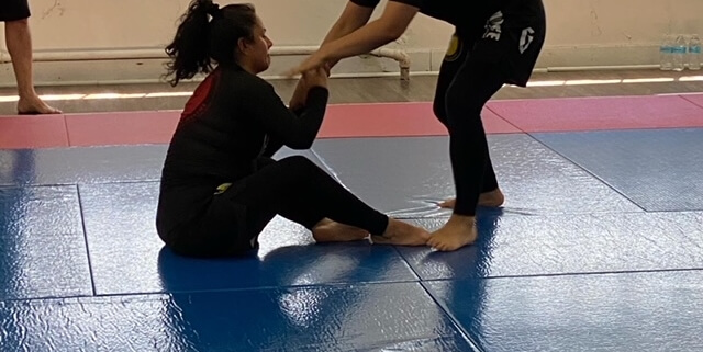 Two women are practicing martial arts in a gym.