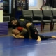 Two people are wrestling on a blue mat.