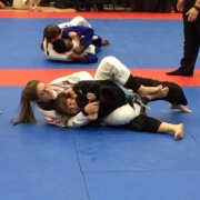 Two women are wrestling on a blue and red mat.