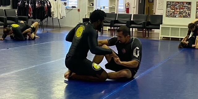 Two men are practicing jiu jitsu in a gym.