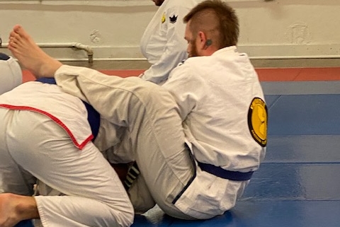 Two men in white and blue uniforms practicing jiu jitsu.