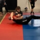 A person is wrestling on the ground in a gym.