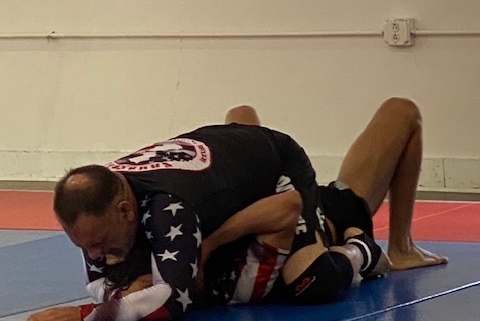 A man is wrestling on the ground in an indoor gym.
