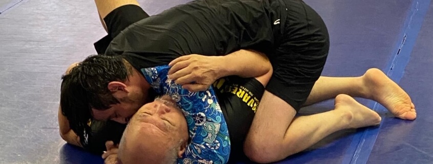 Two people are wrestling on a blue floor.
