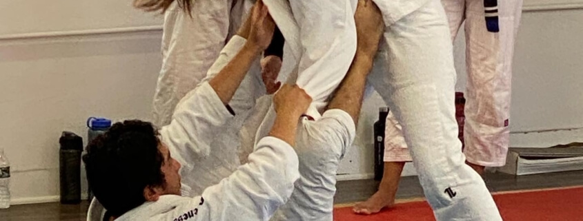 A woman is doing judo moves on the ground