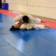 A man is wrestling on the ground in a judo gym.