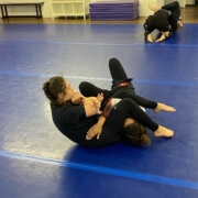 Two people are wrestling on a blue floor.