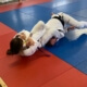 A woman is lying on the ground in a judo gym.