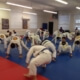 A group of people in white uniforms doing martial arts moves.