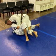 Two men are practicing judo on a blue mat.