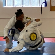 A woman is wrestling with another person in a white uniform.