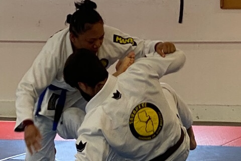 A woman is wrestling with another person in a white uniform.