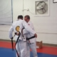 Two men in white and black uniforms are practicing judo.