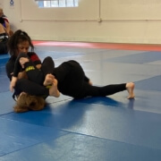 A woman is wrestling on the ground in a gym.