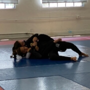 Two people are wrestling on a blue mat.