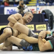 Two men wrestling on a mat in an arena.