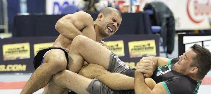 Two men wrestling on a mat in an arena.