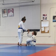 Two people in a judo gym one is holding a board