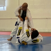 Two men practicing martial arts in a gym.