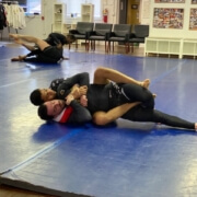 Two men are wrestling on a blue mat.