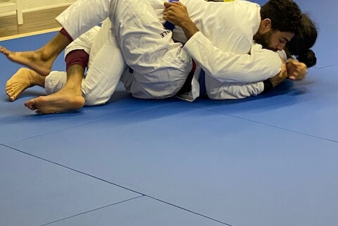 Two people are practicing judo on a blue mat.