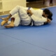 Two people are practicing judo on a blue mat.
