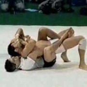 Two men are wrestling on a white mat.