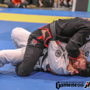 Two men are wrestling on a blue mat.